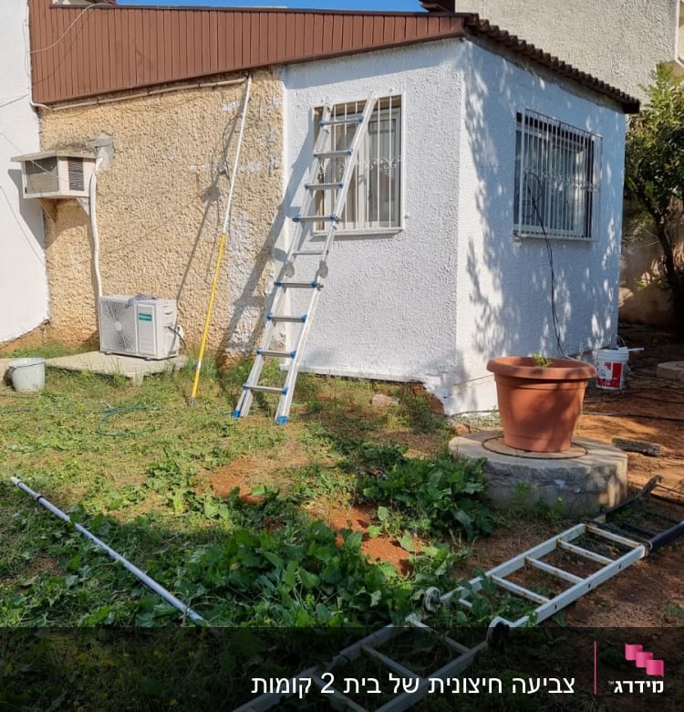 סולם ליד קיר צבוע בלבן עם חלון